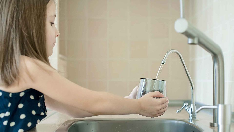 Girl using filter to purify drinking clean water.